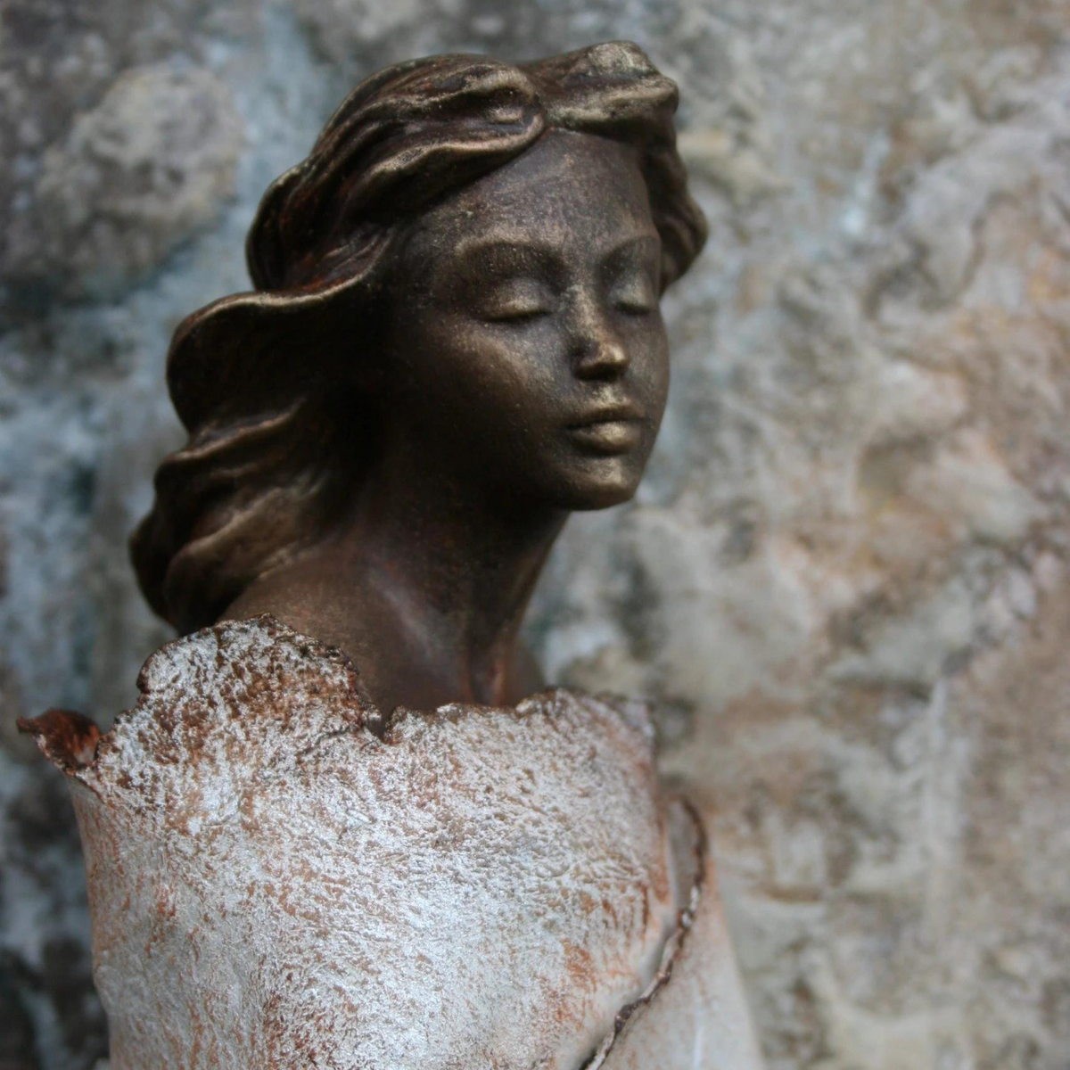 Plaster Bust Marjani with the bodice wrapped in Powertex Universal Medium and Stone Art clay, shown against a stone wall